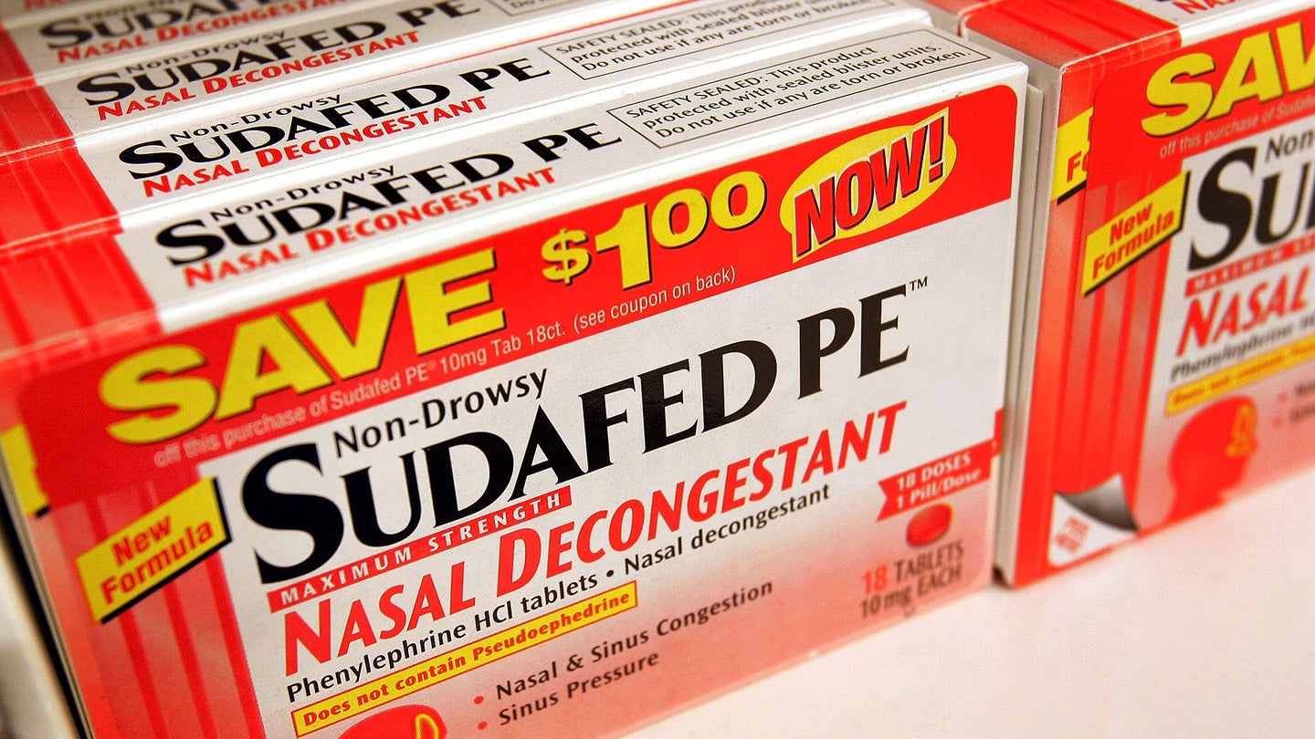 A box of a nasal decongestant called SudafedPe on a store shelf.