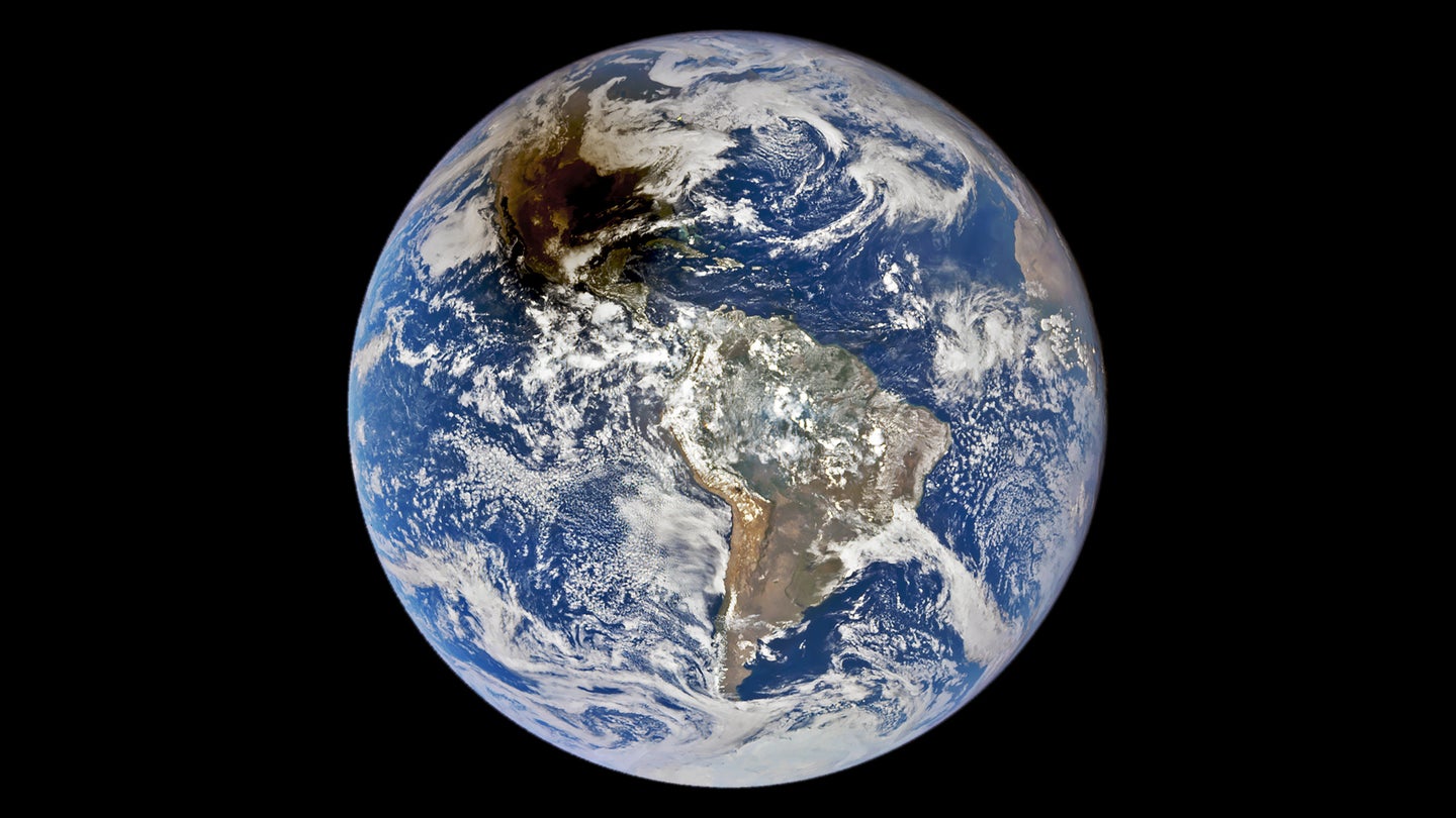 The planet Earth, as seen from the DSCOVR satellite. Earth appears as a bright blue dot against the darkness of space, with the shadow of an annular solar eclipse over much of North America.